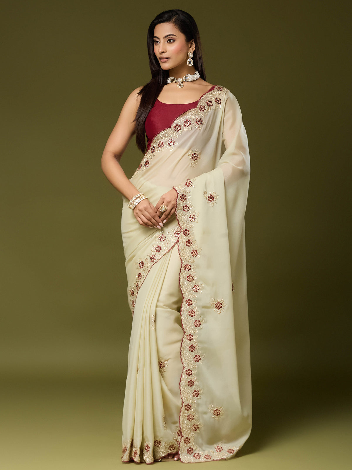 Woman wearing cream georgette saree with embroidered motif work and maroon blouse