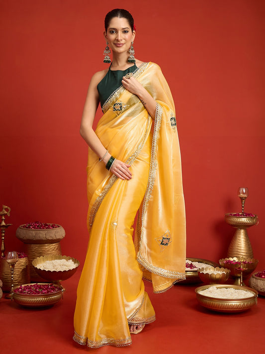 Woman wearing yellow paper silk saree with ornamented surface design and green blouse