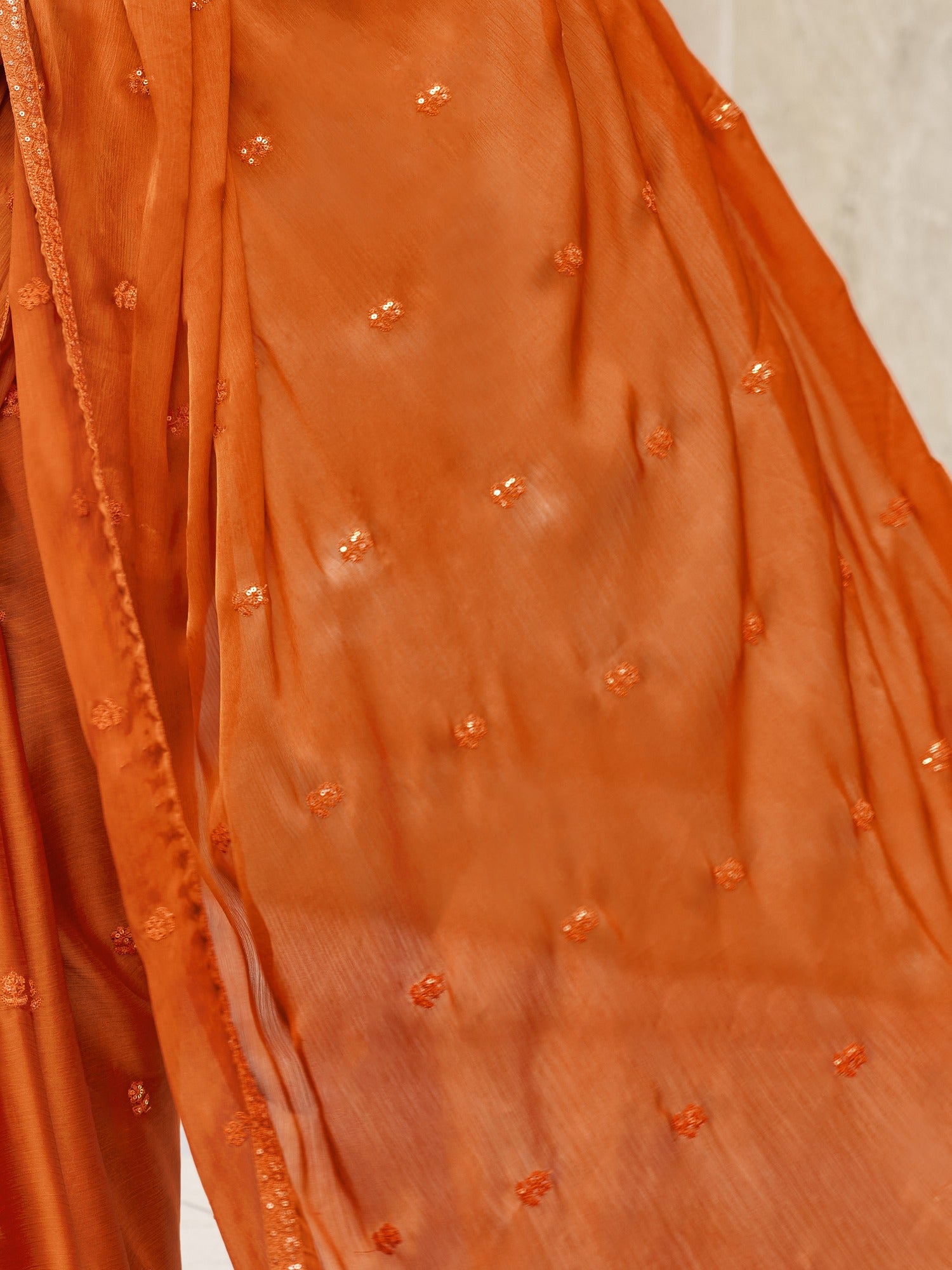 Pallu detail of rust satin silk saree showing ornamented surface design and embellished border