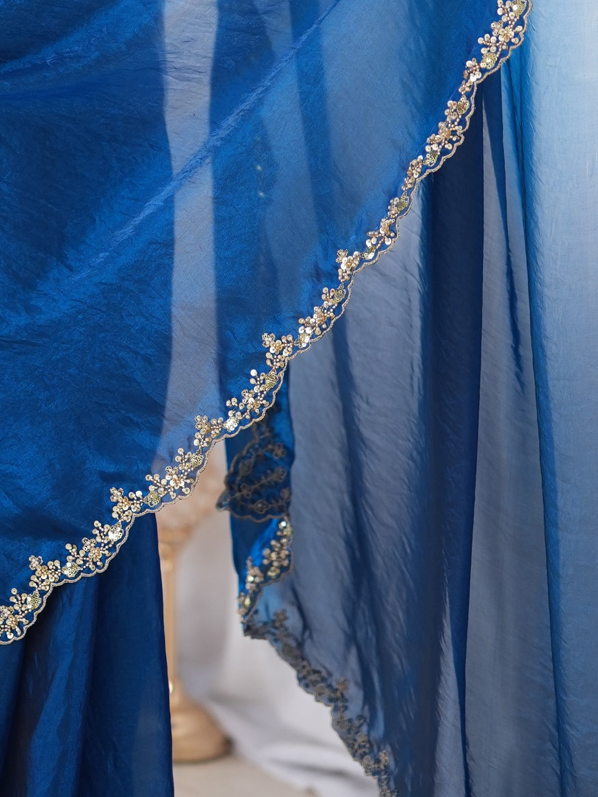 Pallu detail of teal blue satin saree showing clean solid-tone finish and scallop border