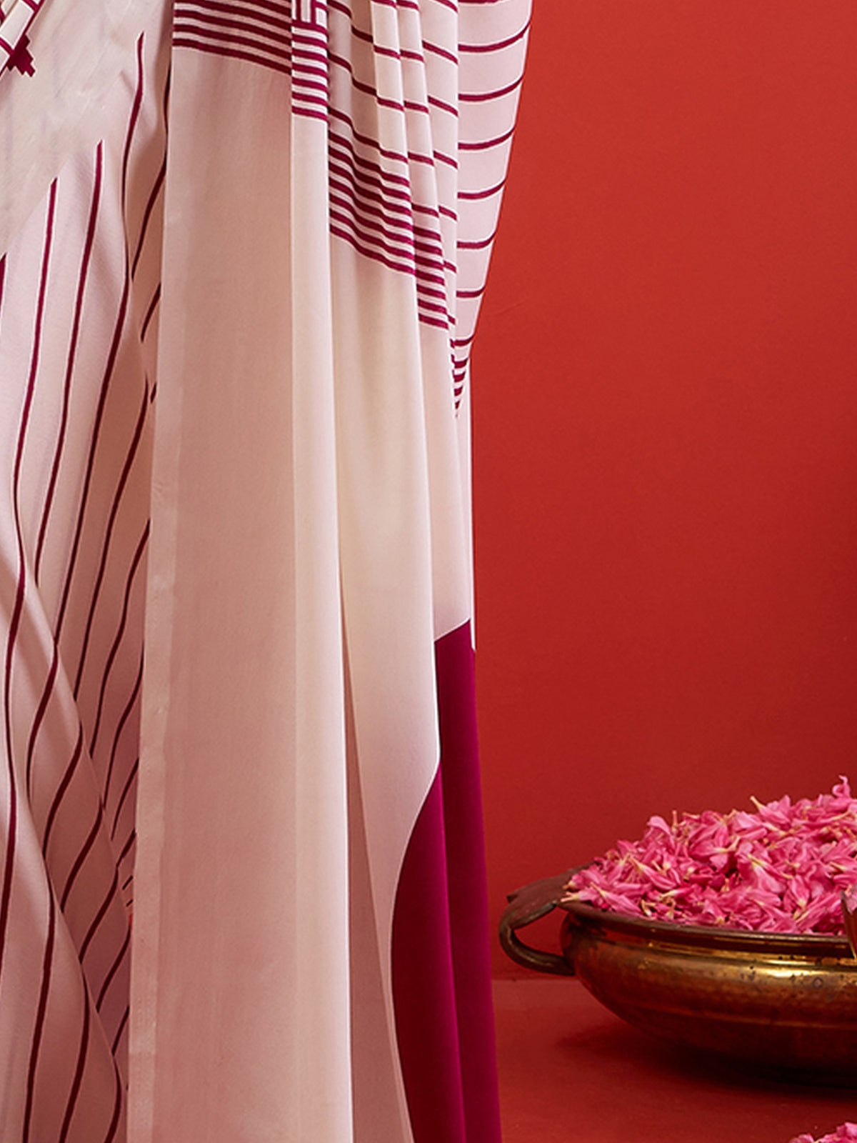 Pallu detail of white satin saree showing striped pattern design and printed border