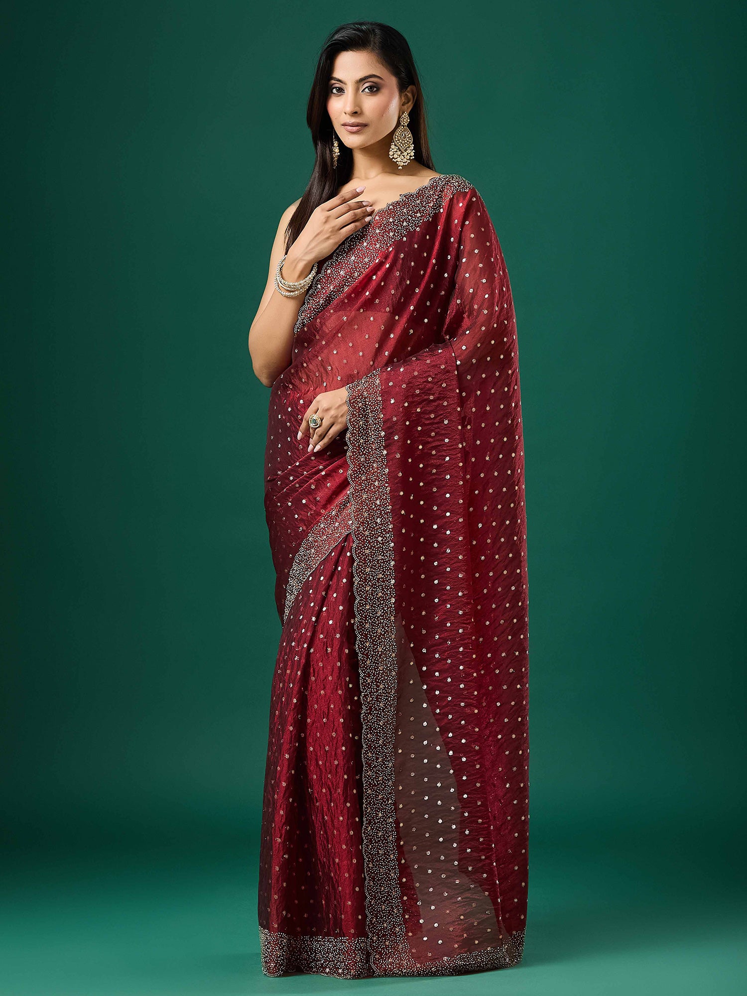 Woman wearing maroon silk blend saree with ornamented surface design and maroon blouse