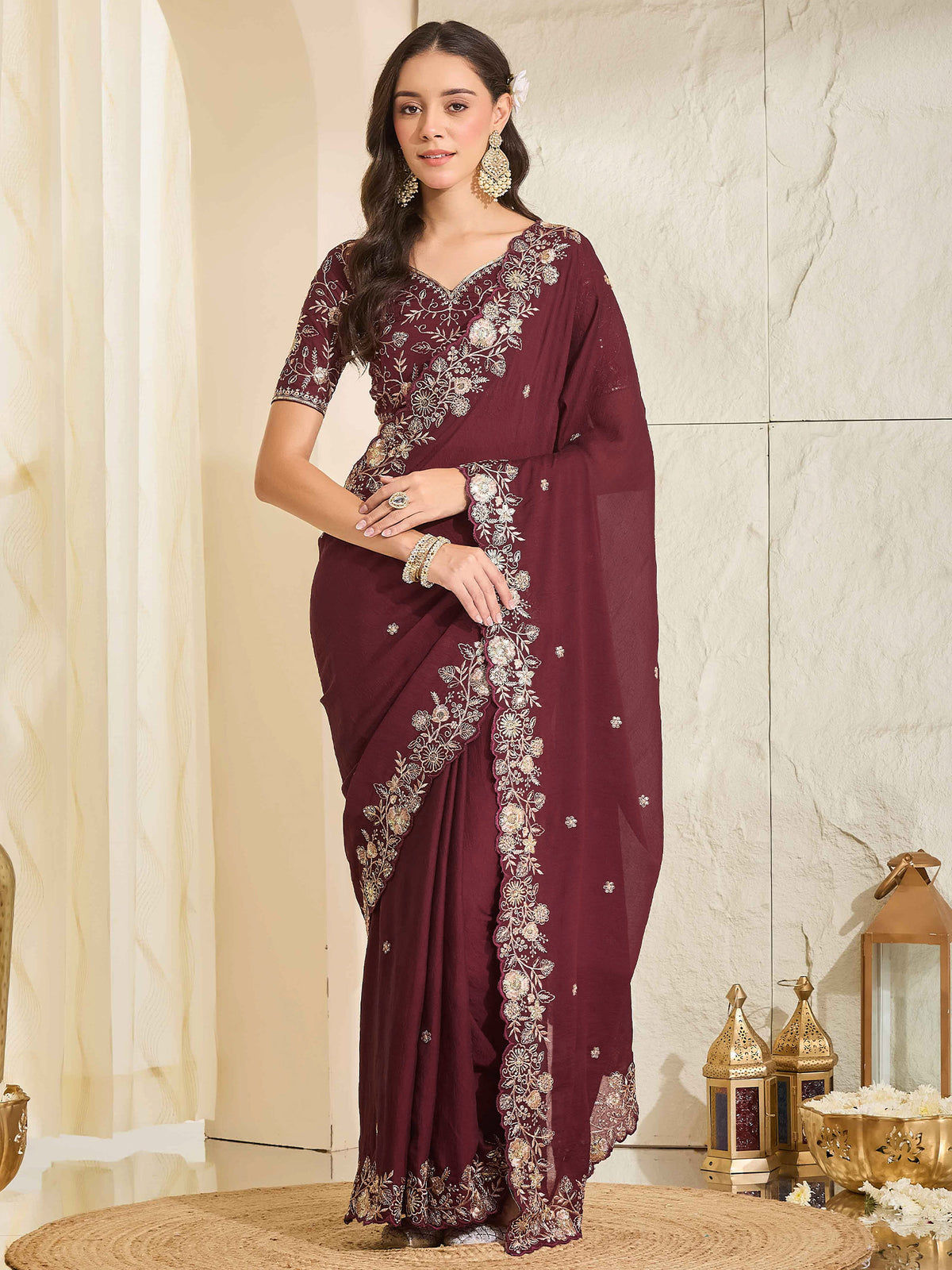 Woman wearing maroon georgette saree with ornamented surface design and maroon blouse