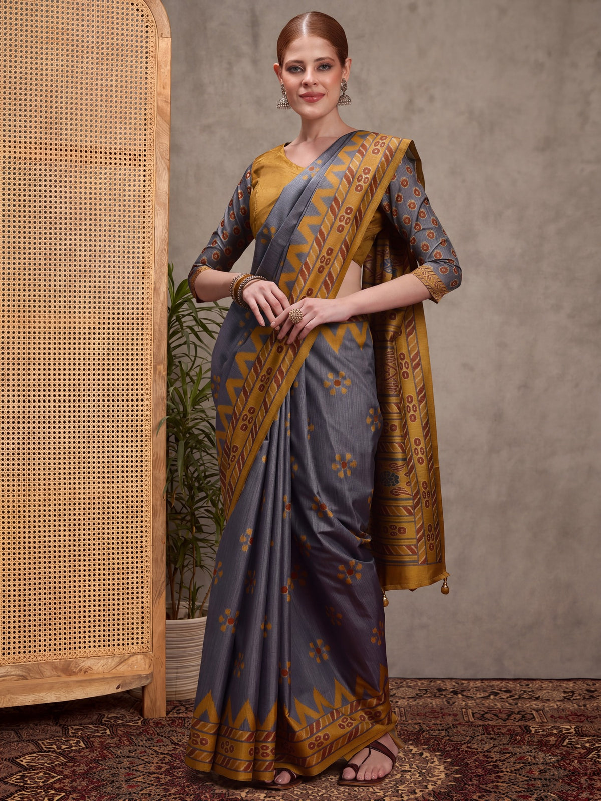 Woman wearing charcoal grey silk blend saree with traditional indian motif work and mustard blouse