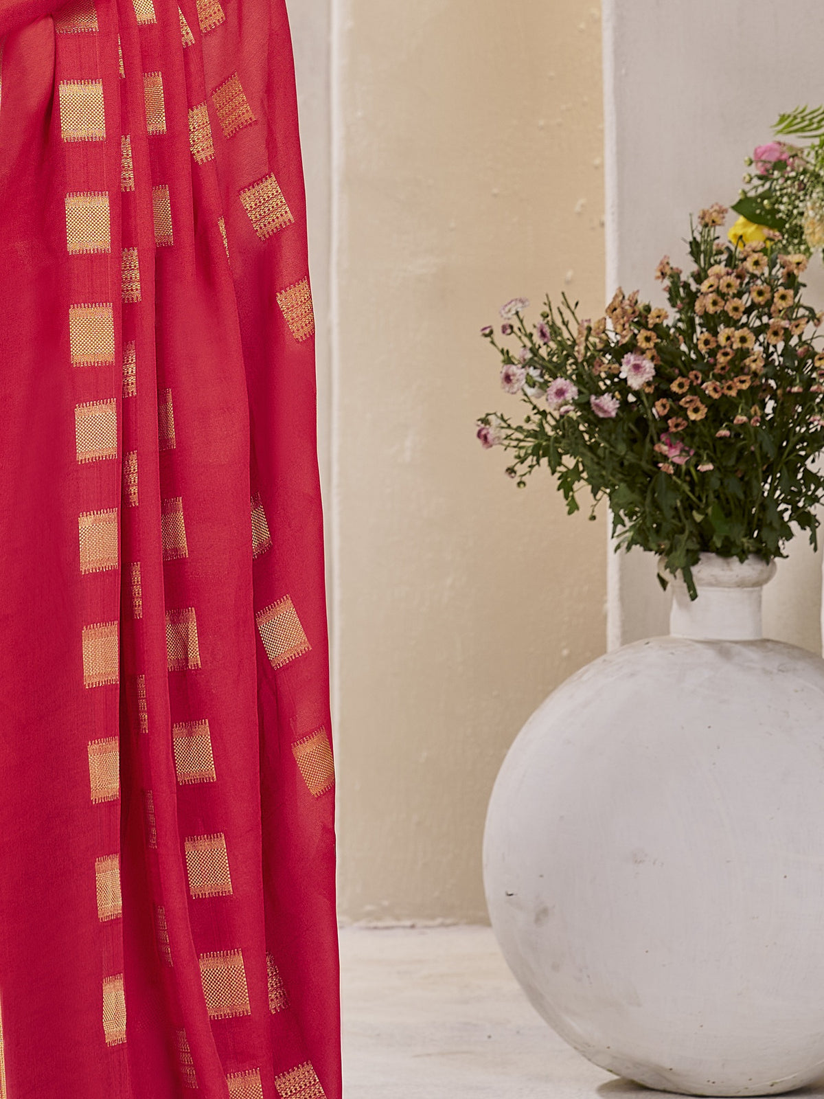 Pallu detail of red georgette saree showing zari butta (metallic motif) work and zari border