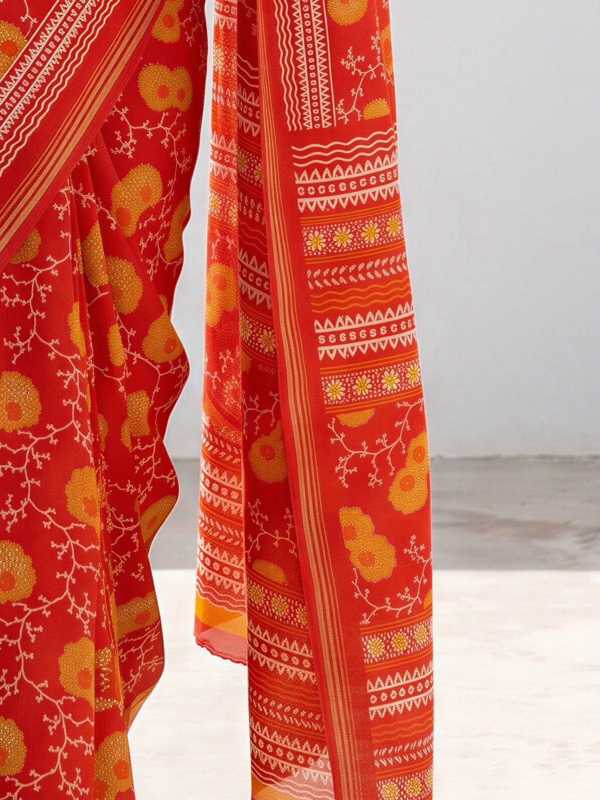 Pallu detail of orange crepe saree showing botanical floral and leaf design and zari border