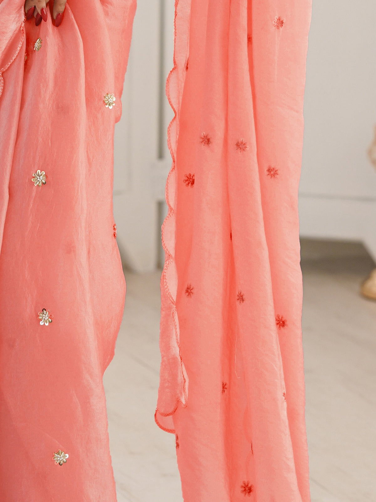 Pallu detail of peach satin saree showing ornamented surface design and embroidered border