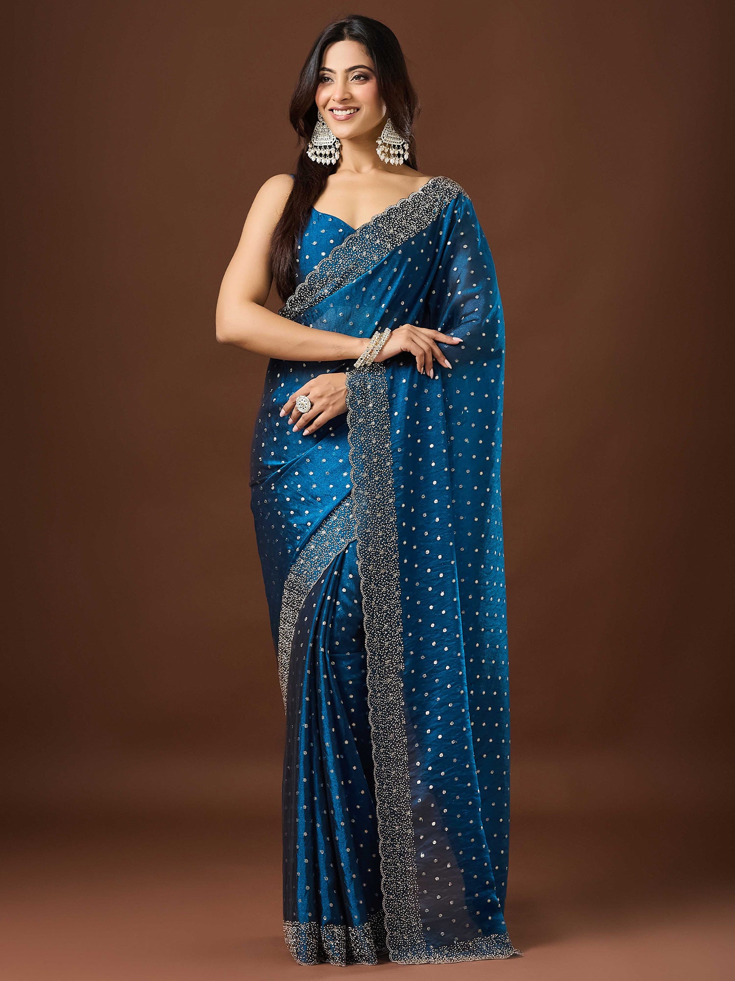 Woman wearing teal blue silk blend saree with ornamented surface design and teal blue blouse