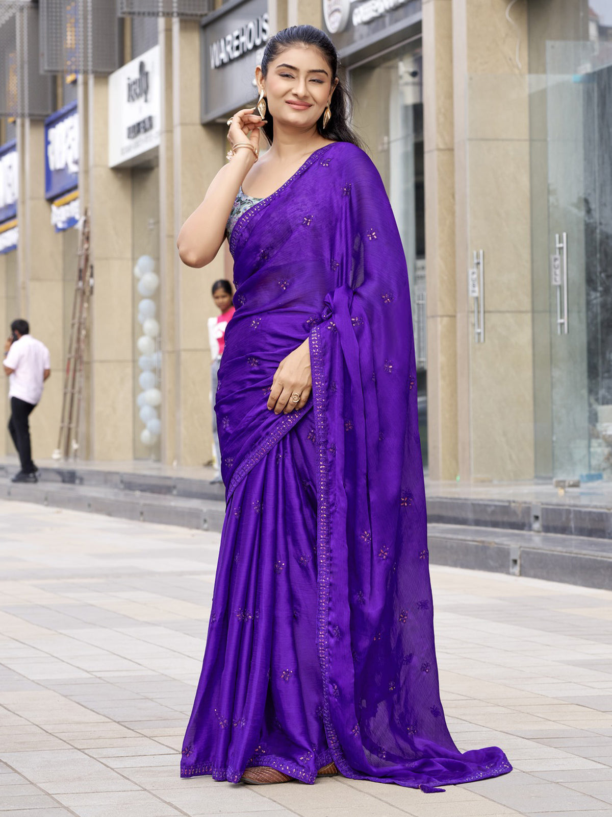 Woman wearing purple satin silk saree with ornamented surface design and multicolored blouse