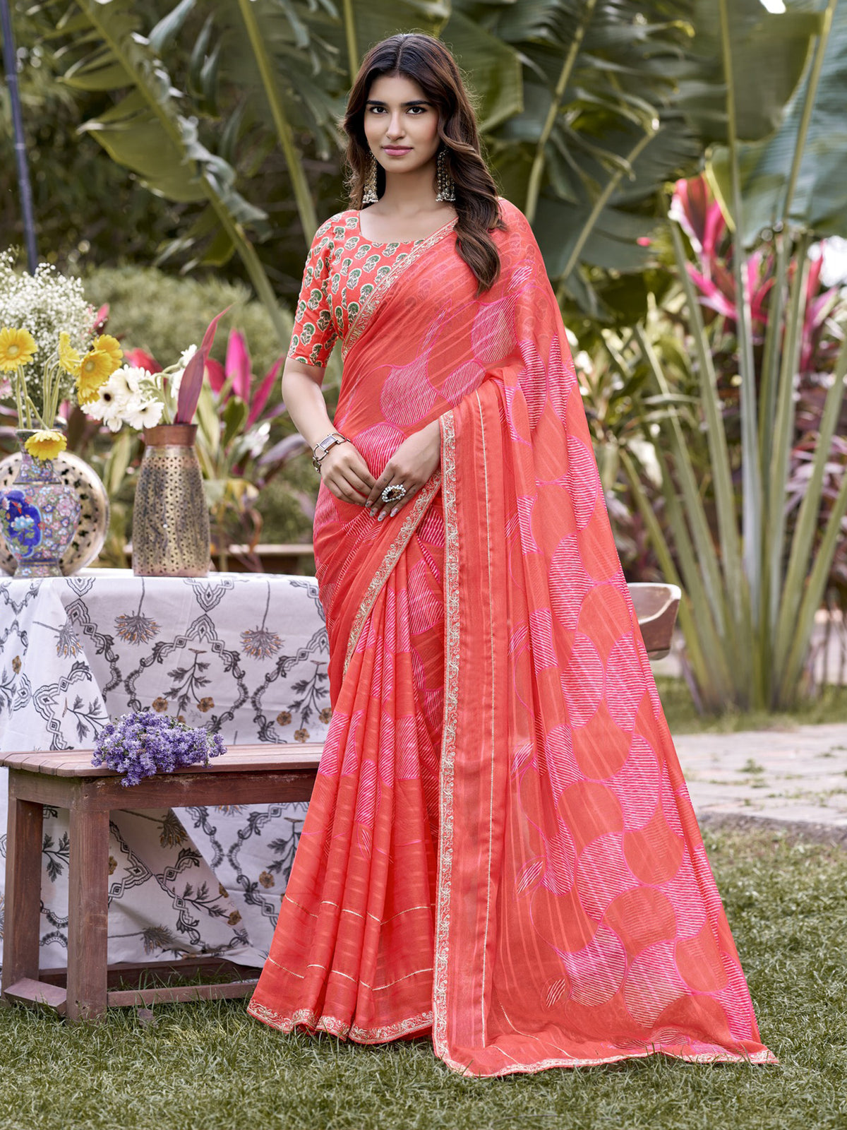 Woman wearing coral chiffon saree with traditional indian motif work and coral blouse
