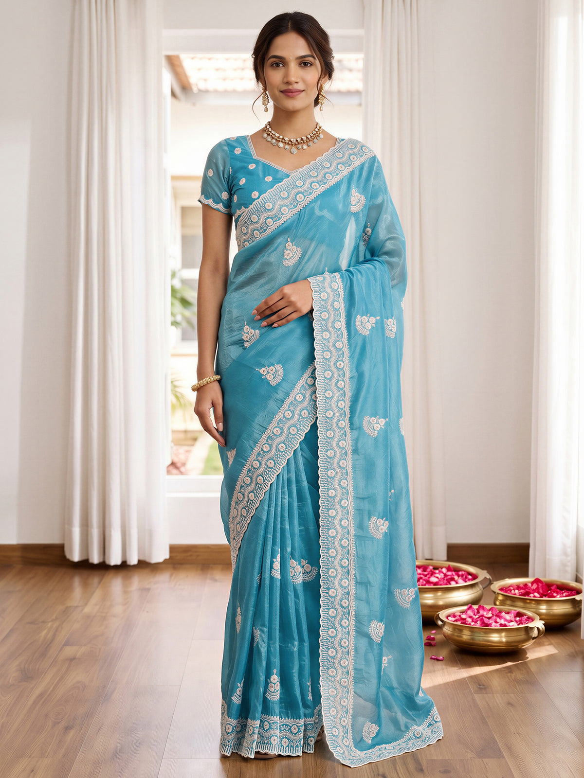 Woman wearing light blue paper silk saree with ornamented surface design and light blue blouse