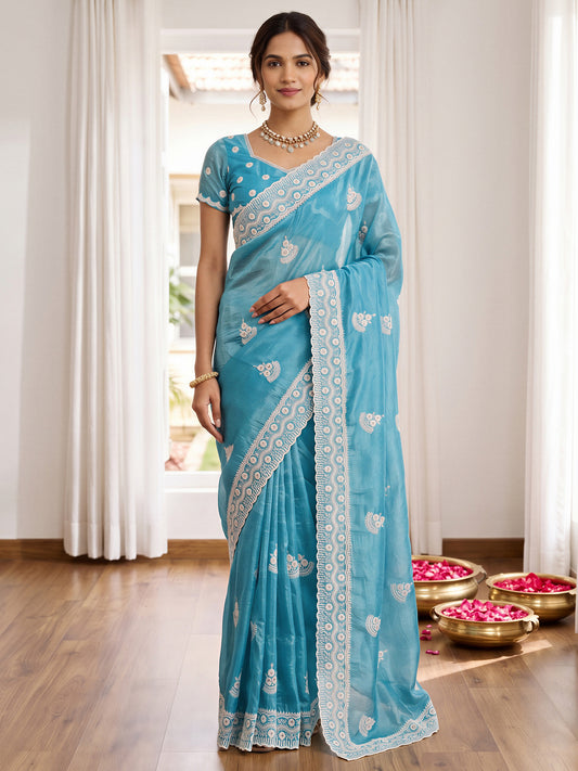 Woman wearing light blue paper silk saree with ornamented surface design and light blue blouse