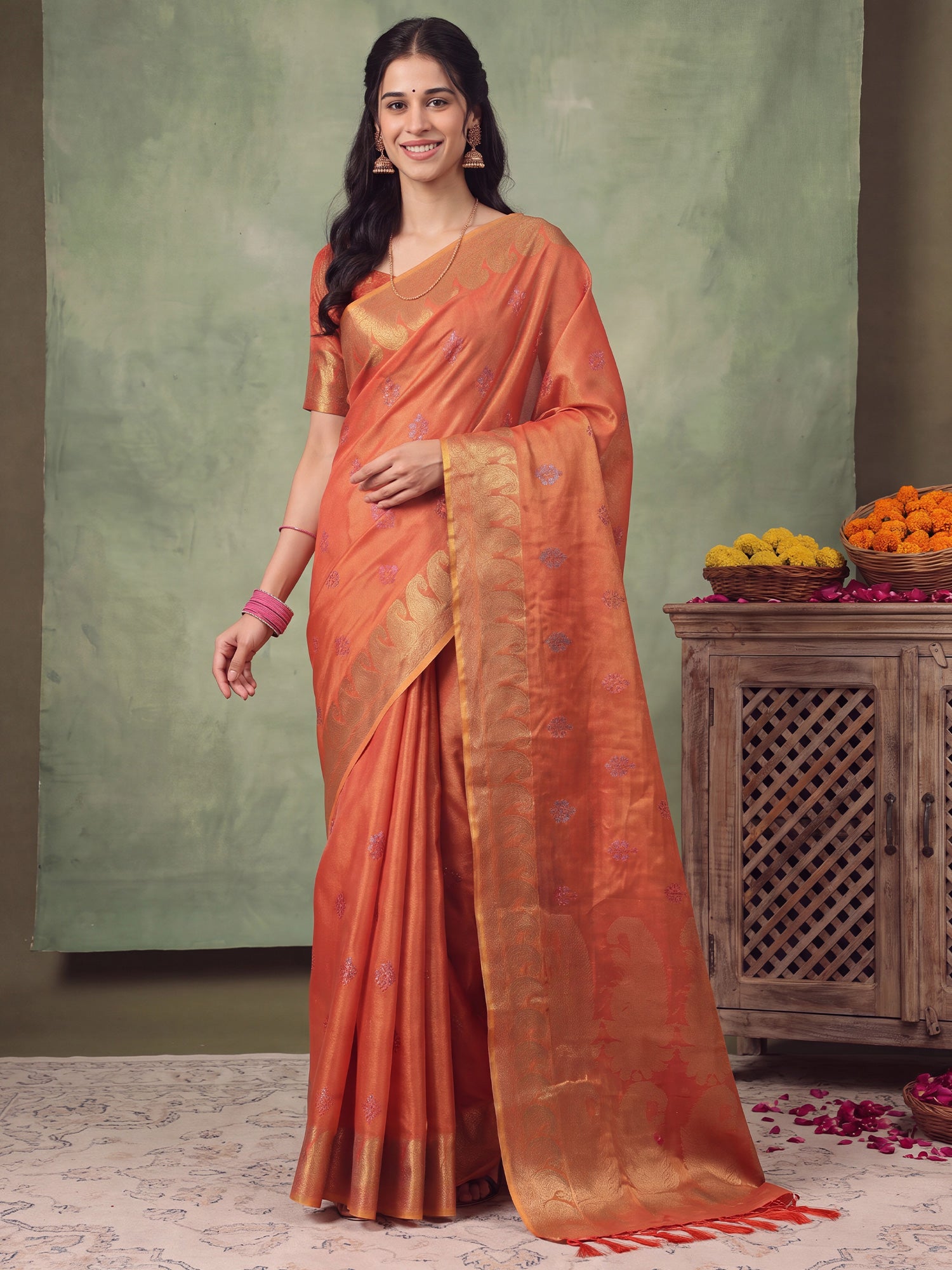Woman wearing rust linen saree with traditional indian motif work and rust blouse