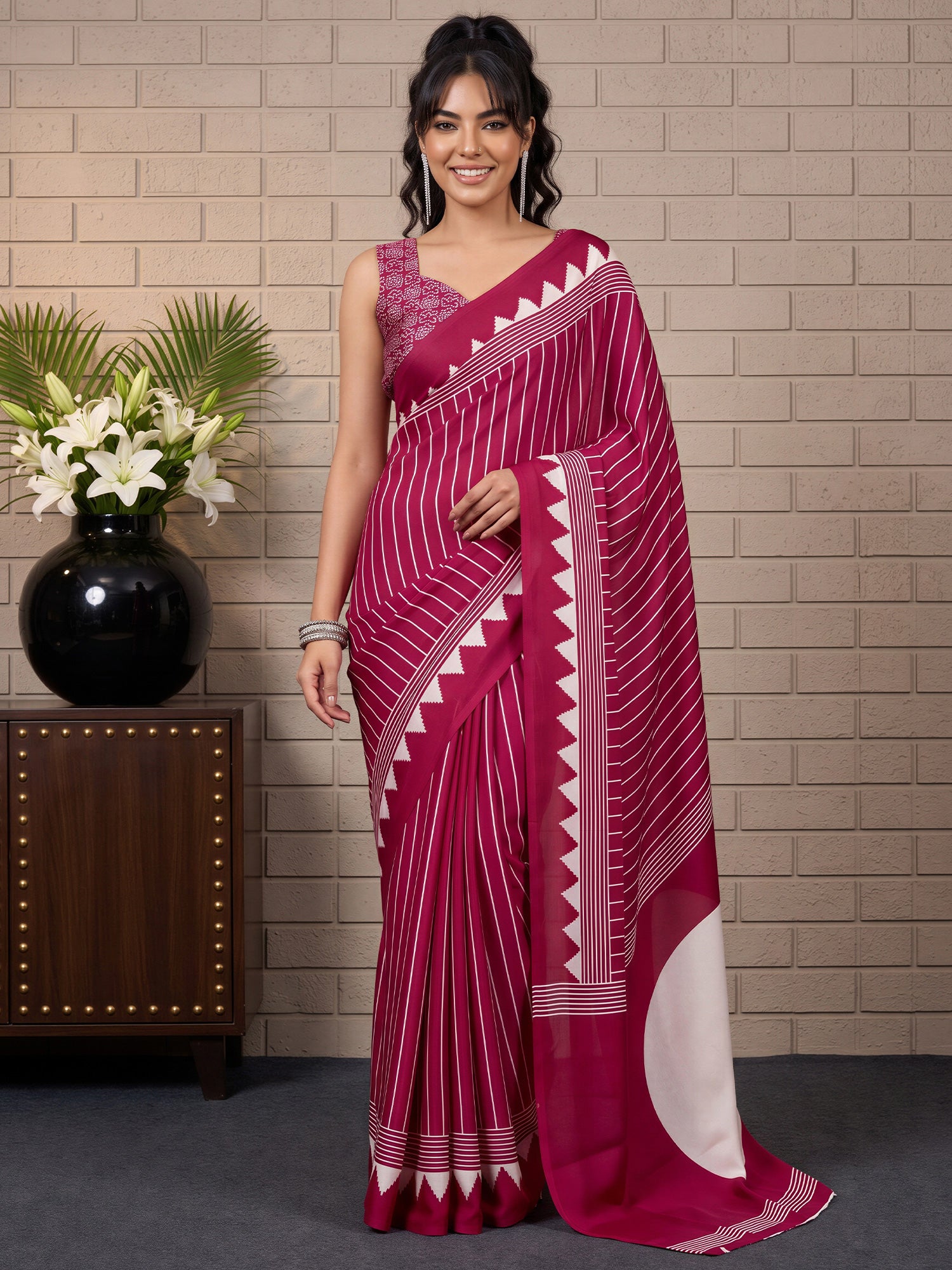 Woman wearing burgundy satin saree with striped pattern design and burgundy blouse