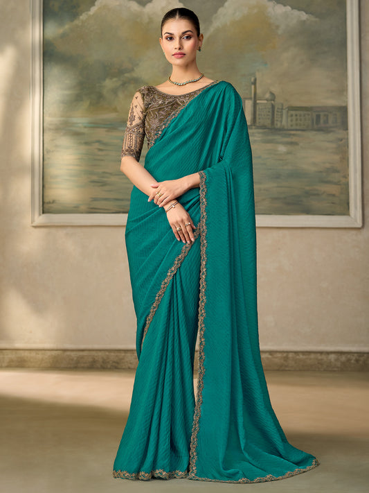 Woman wearing teal green satin silk saree with embroidered motif work and grey blouse