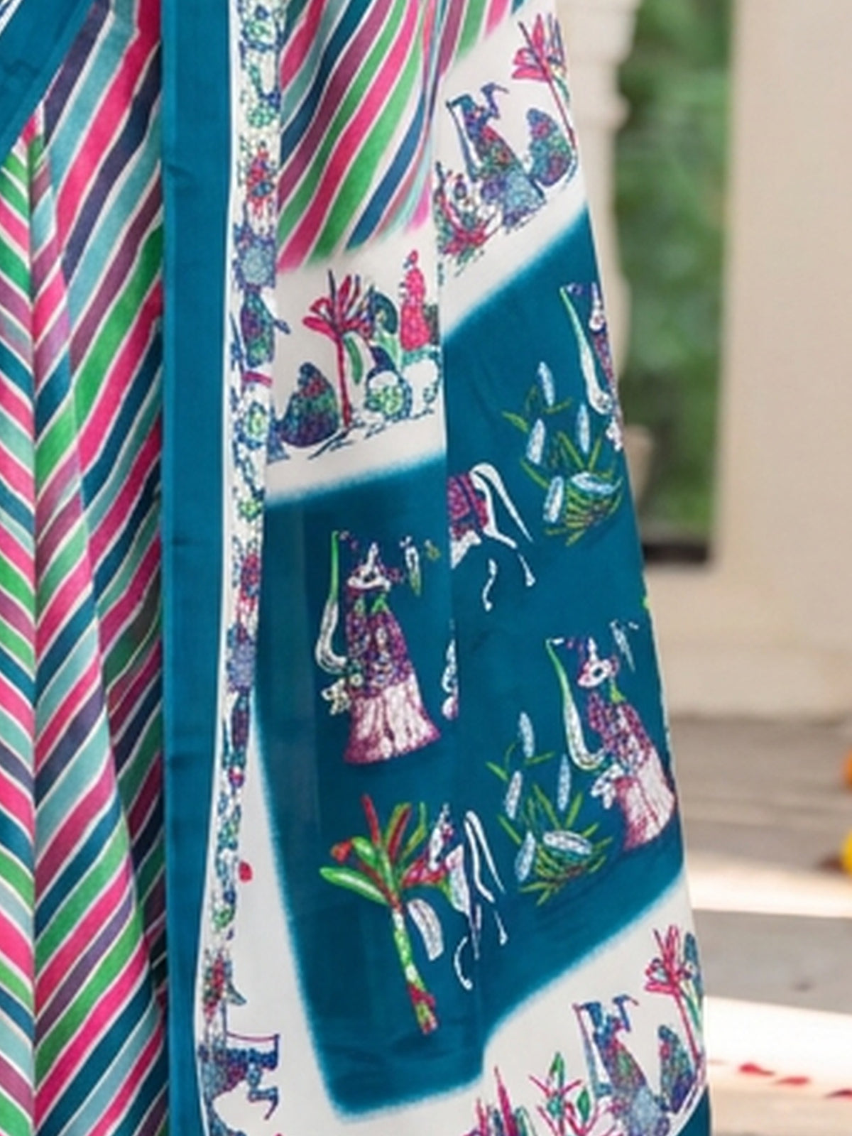 Pallu detail of teal crepe saree showing striped pattern design and printed border