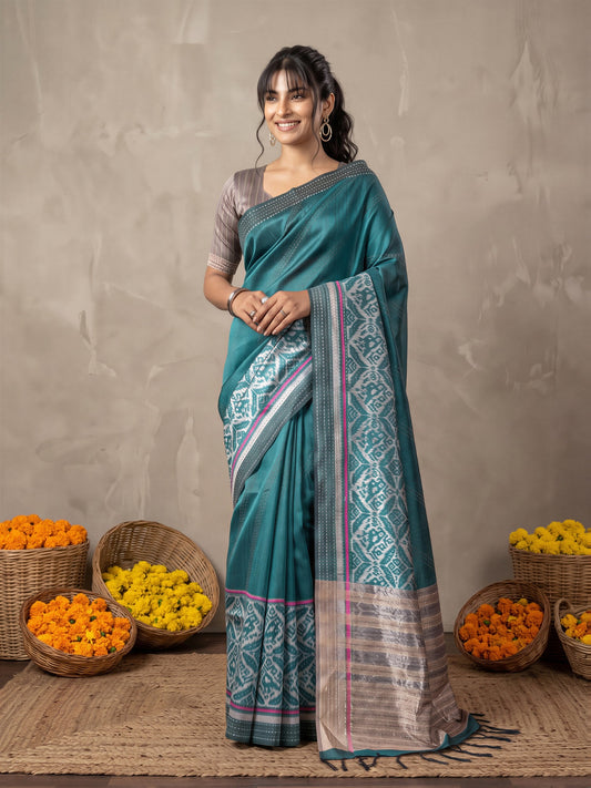 Woman wearing teal blue silk cotton saree with ikat resist-dyed pattern and grey blouse