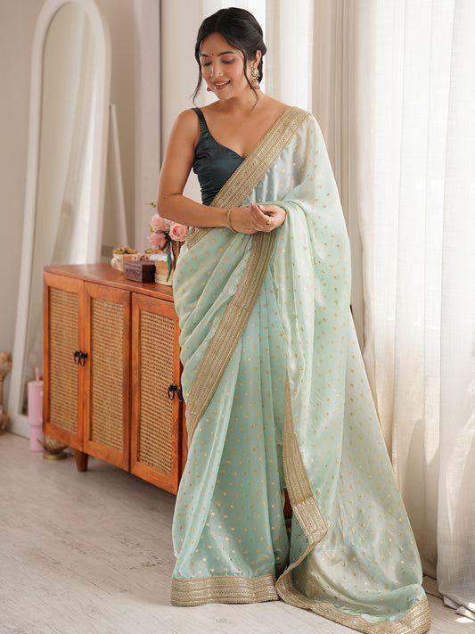 Woman wearing light blue silk blend saree with zari butta (metallic motif) work and sea green blouse