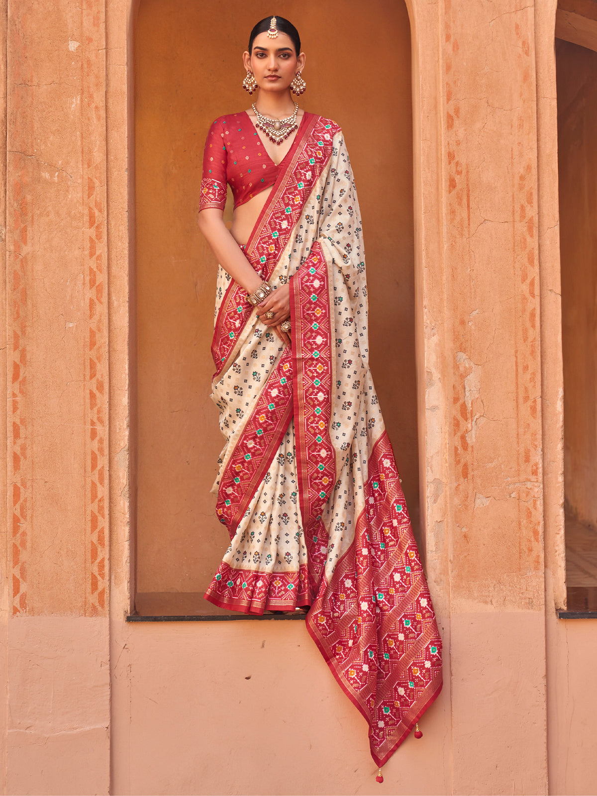 Woman wearing cream silk blend saree with ikat resist-dyed pattern and red blouse