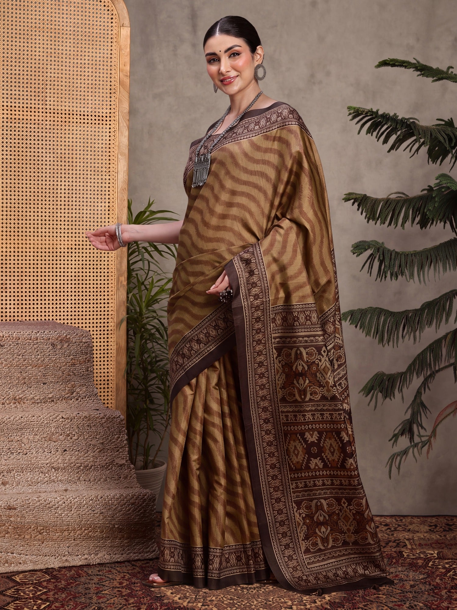 Woman wearing light brown silk blend saree with traditional indian motif work and dark brown blouse