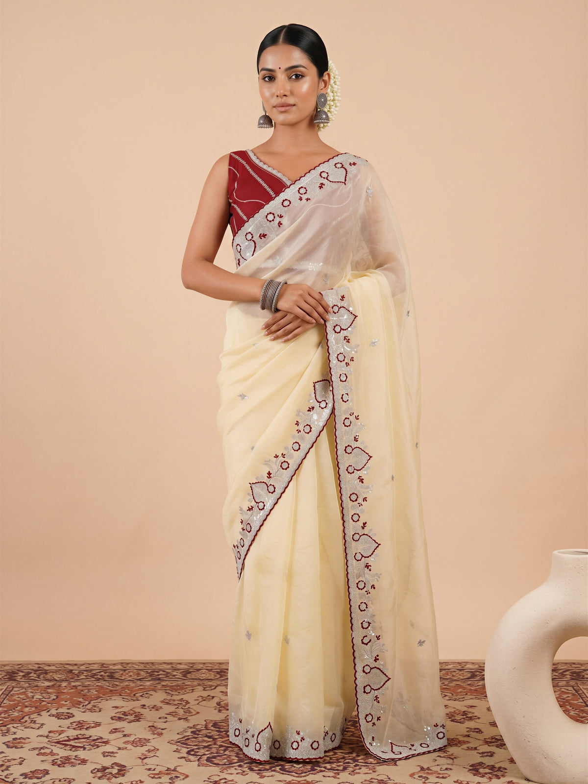 Woman wearing off white tissue saree with embroidered motif work and maroon blouse