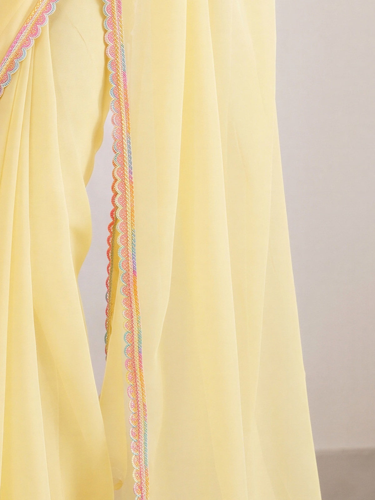 Pallu detail of yellow satin silk saree showing clean solid-tone finish and embellished border