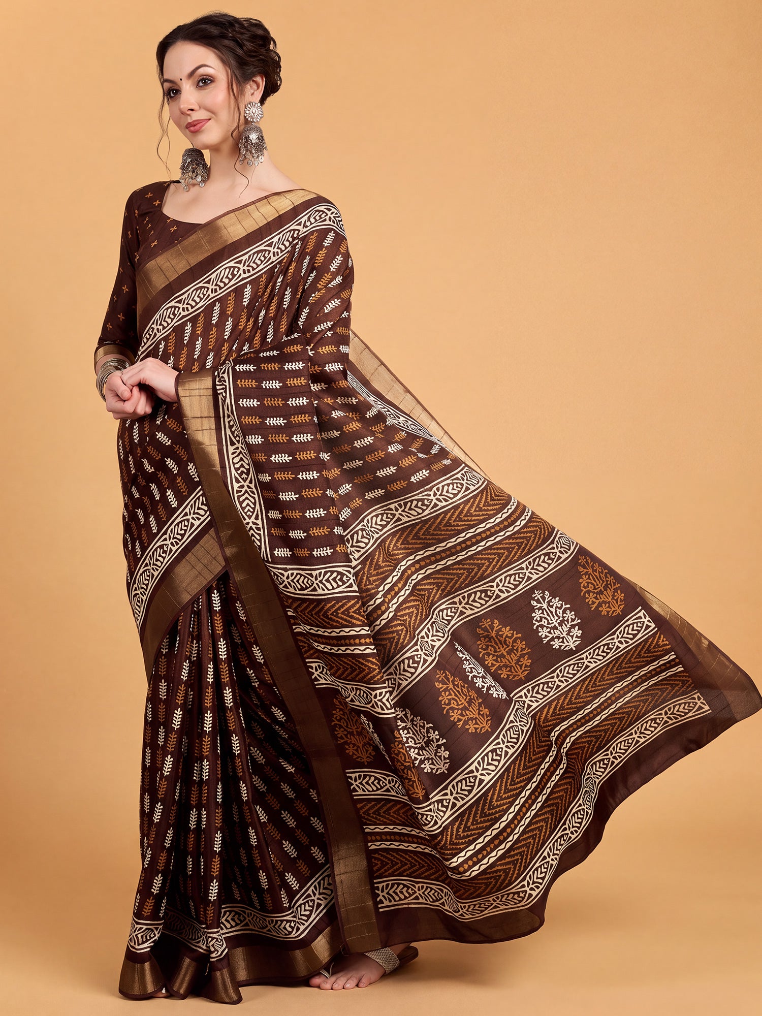 Woman wearing brown silk blend saree with traditional indian motif work and brown blouse