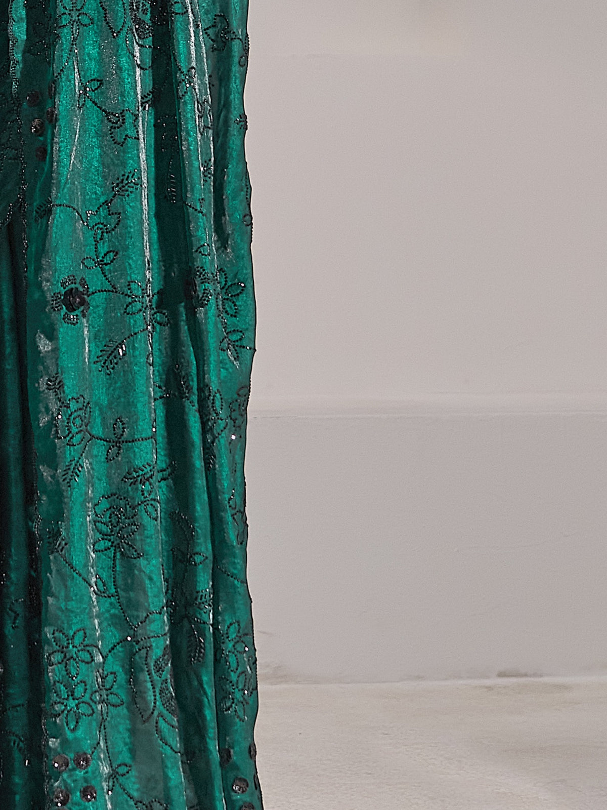 Pallu detail of teal green satin silk saree showing ornamented surface design and embellished border