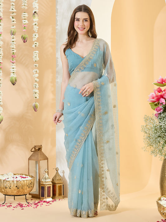 Woman wearing light blue tissue saree with ornamented surface design and light blue blouse
