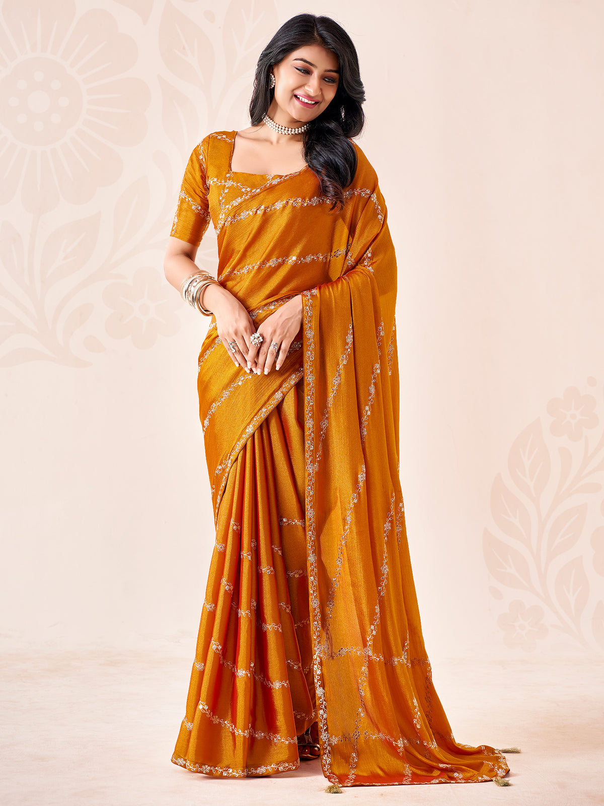 Woman wearing mustard chiffon saree with ornamented surface design and mustard blouse