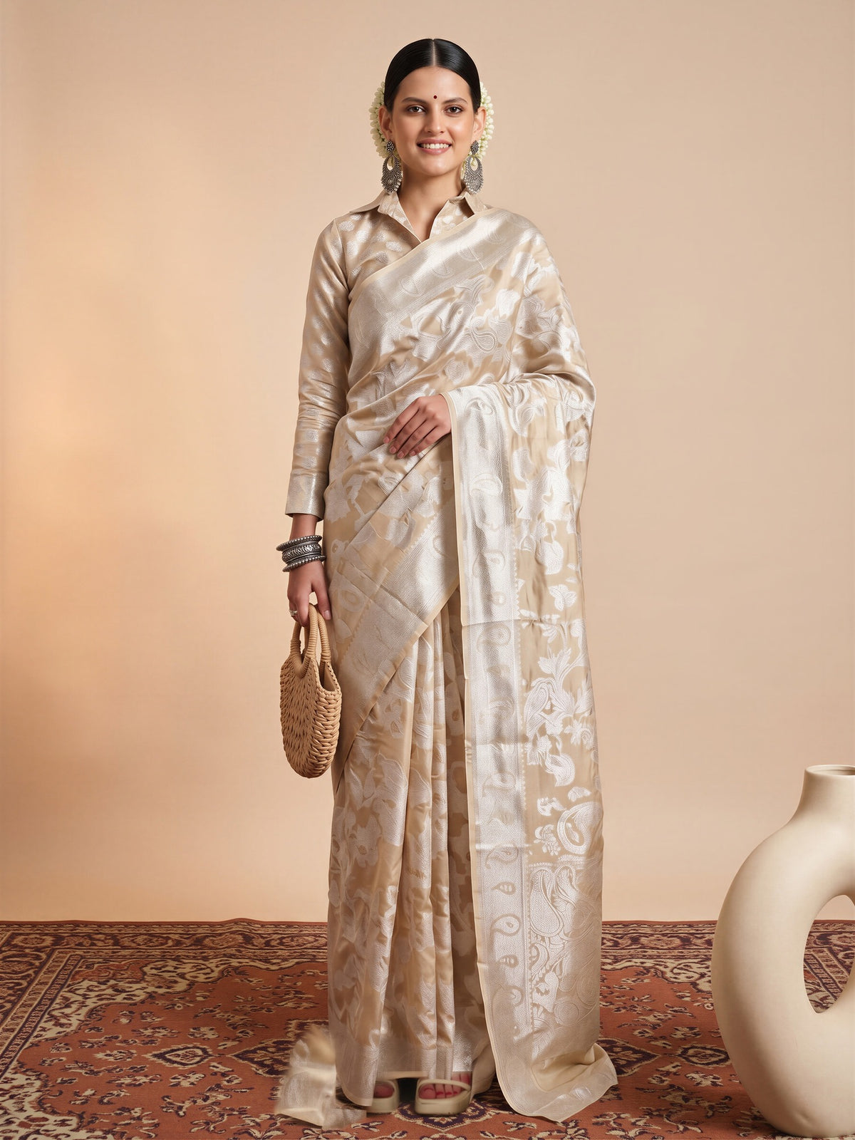 Woman wearing cream organza saree with traditional indian motif work and cream blouse