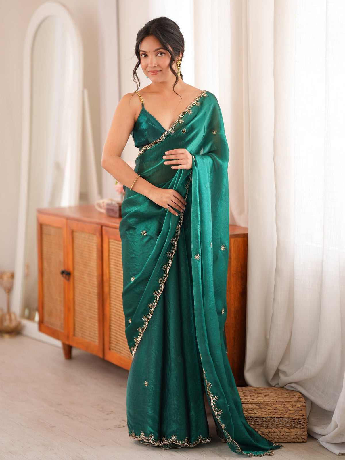 Woman wearing teal green satin saree with ornamented surface design and teal green blouse
