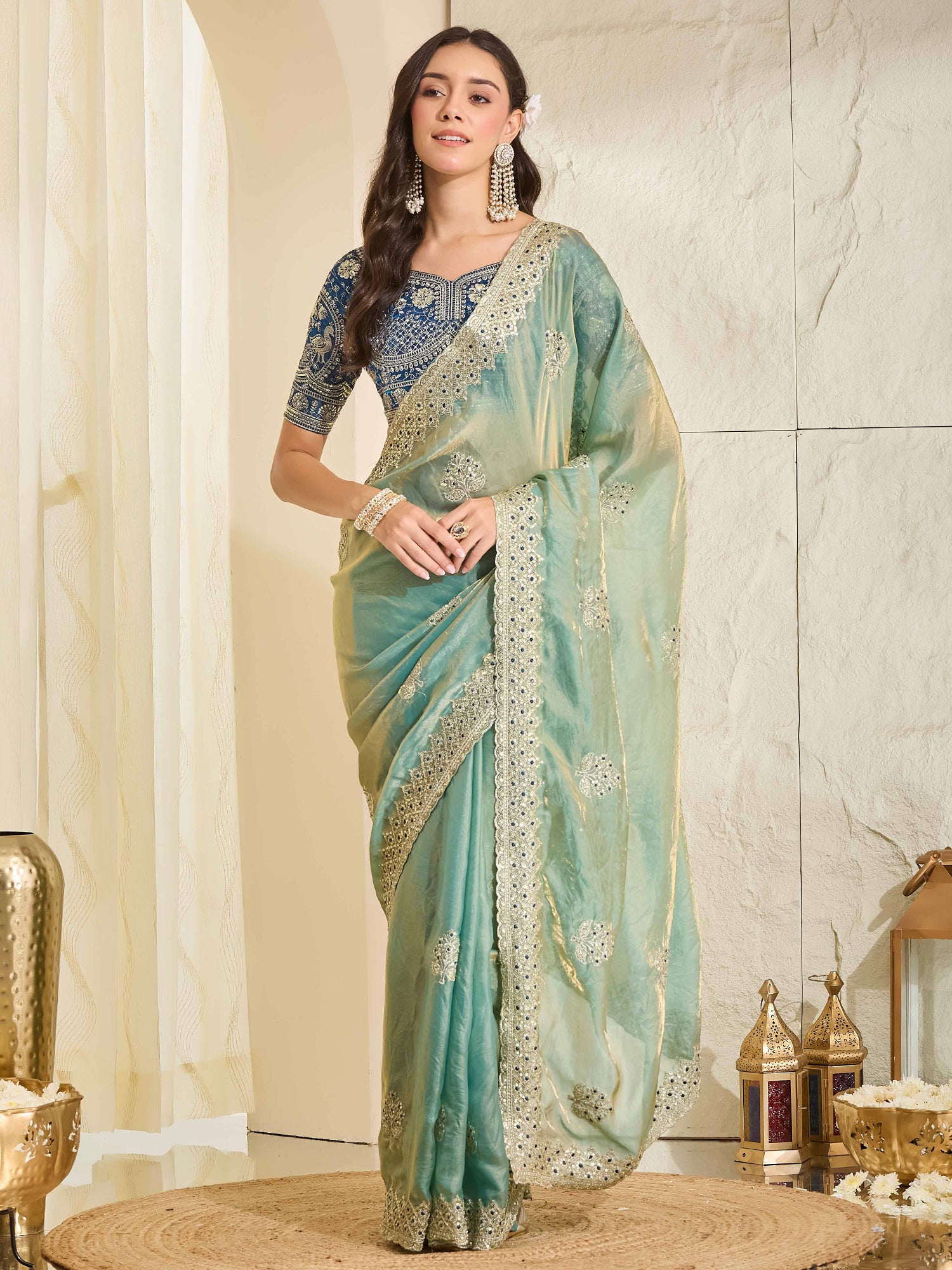 Woman wearing light blue satin saree with ornamented surface design and navy blue blouse