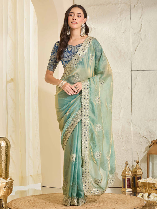 Woman wearing light blue satin saree with ornamented surface design and navy blue blouse
