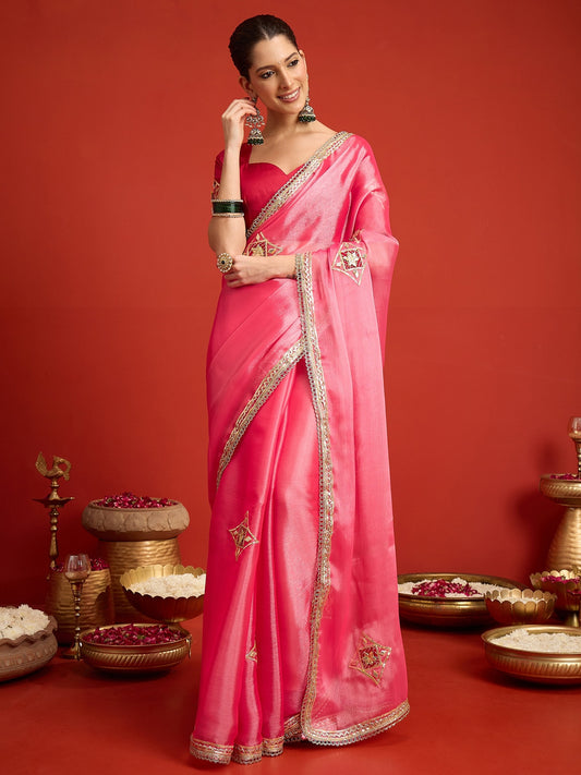 Woman wearing pink paper silk saree with ornamented surface design and pink blouse