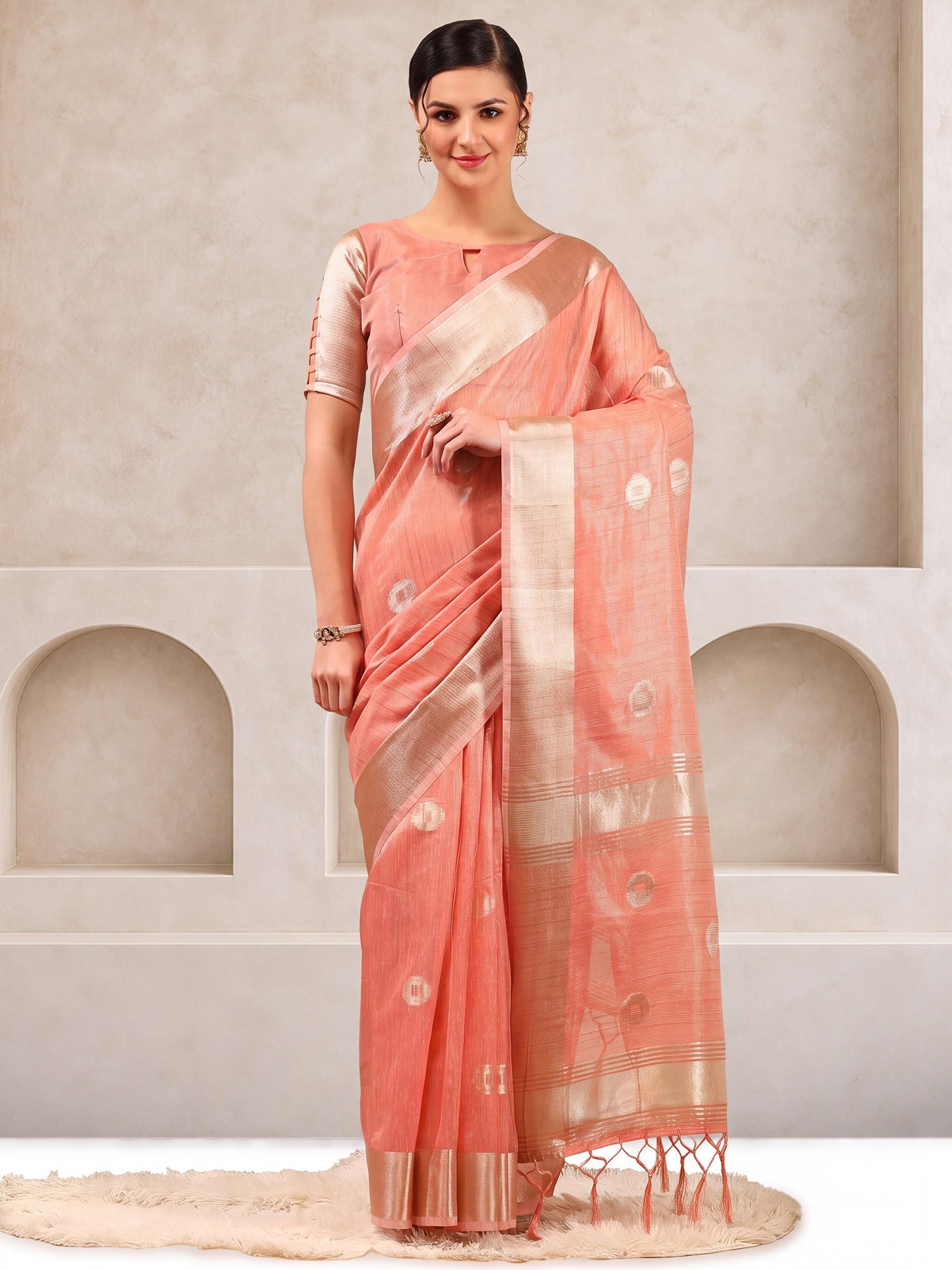 Woman wearing peach linen saree with zari butta (metallic motif) work and peach blouse
