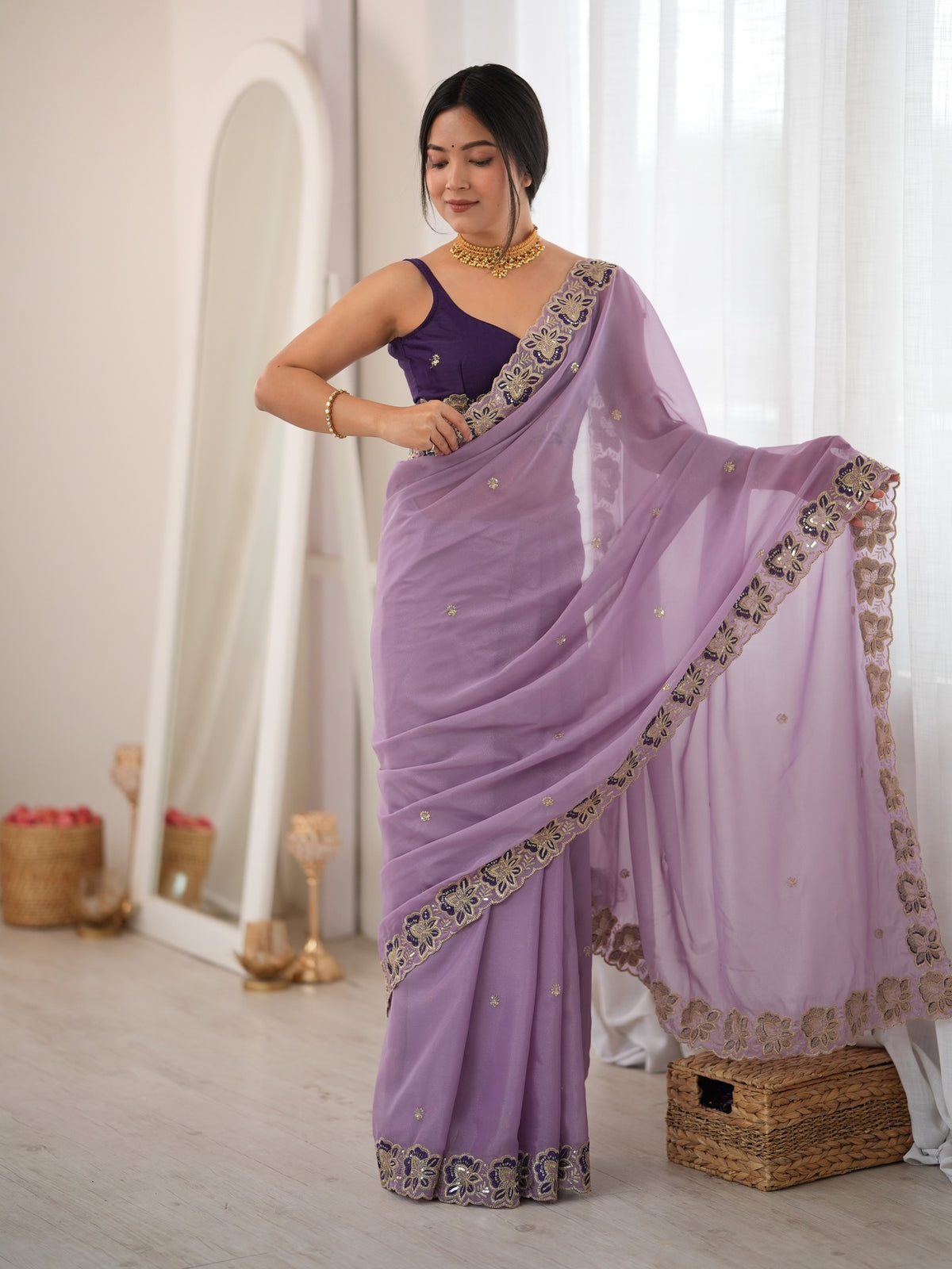 Woman wearing lavender georgette saree with ornamented surface design and purple blouse