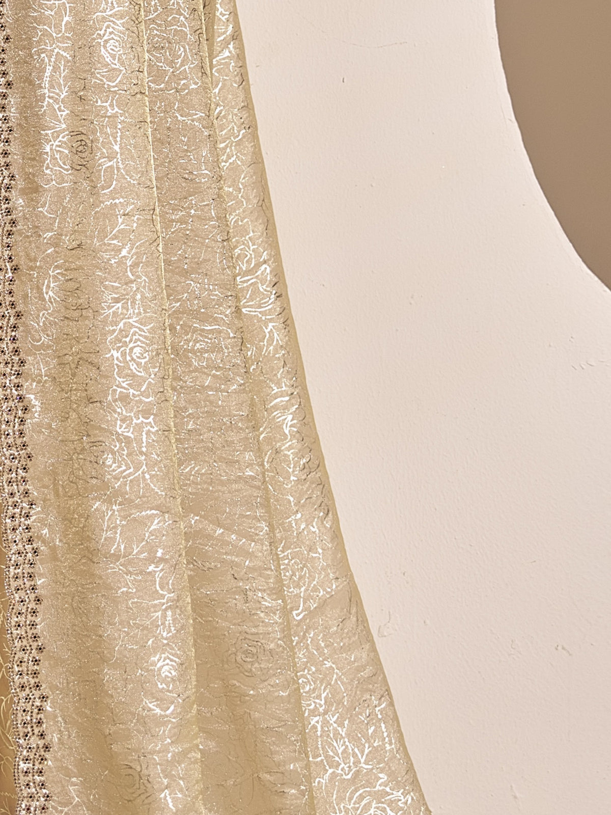 Pallu detail of beige satin silk saree showing metallic foil print work and embellished border
