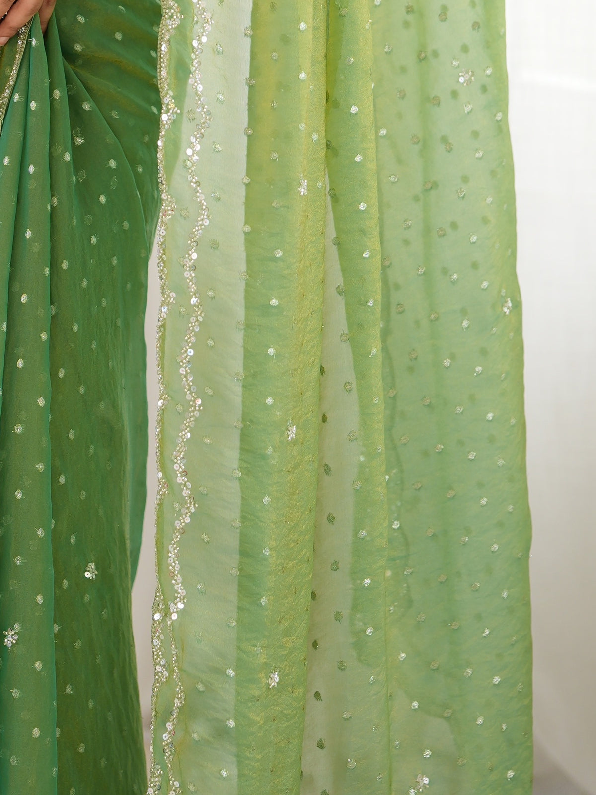 Pallu detail of lime green georgette saree showing zari butta (metallic motif) work and embellished border