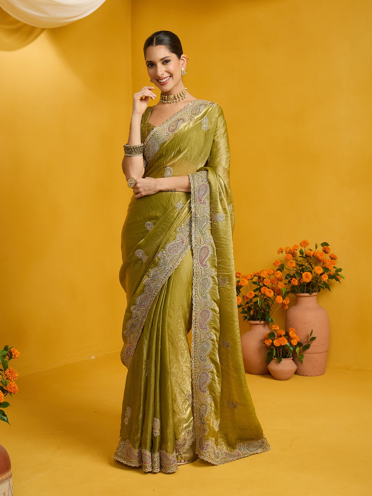 Woman wearing olive satin silk saree with zari butta (metallic motif) work and olive blouse