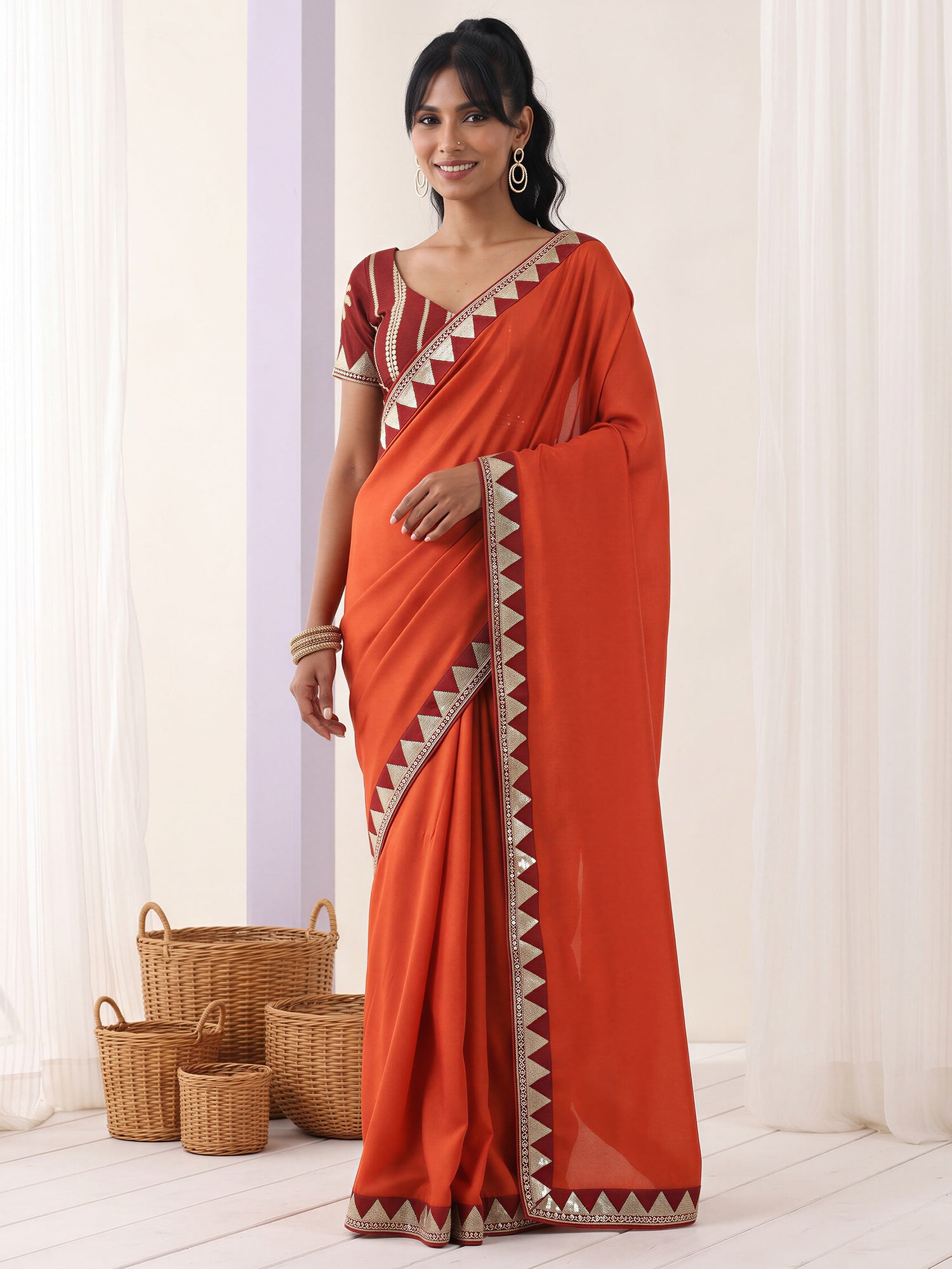 Woman wearing rust vichitra silk saree with embroidered motif work and maroon blouse