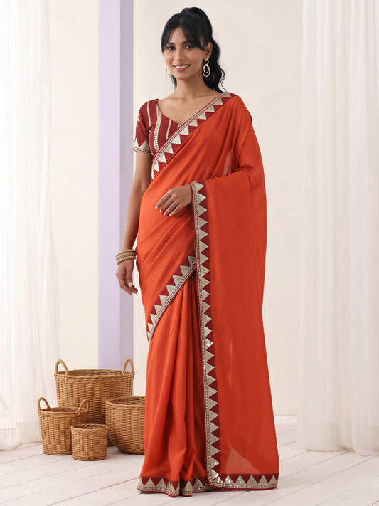 Woman wearing rust vichitra silk saree with embroidered motif work and maroon blouse