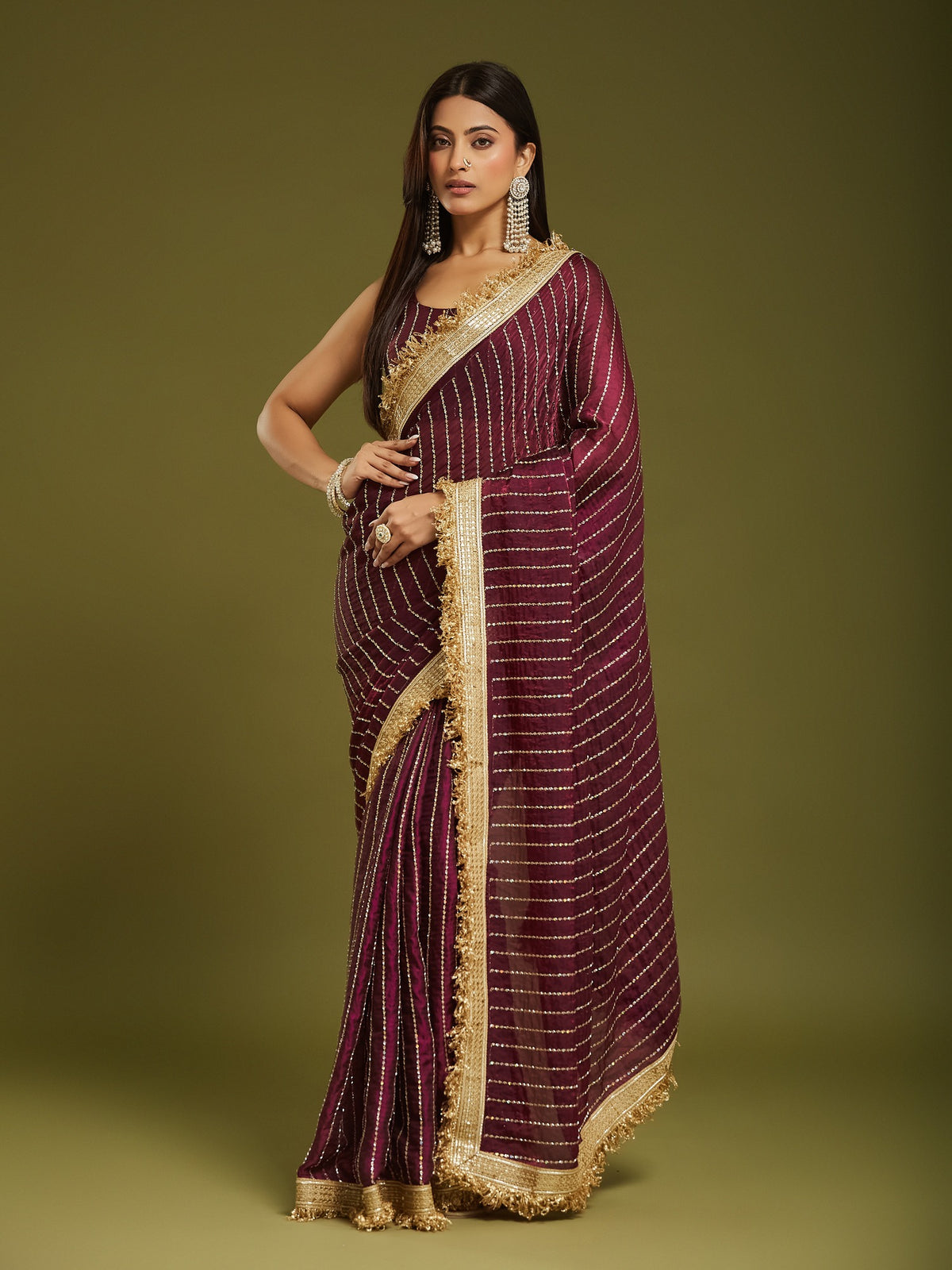 Woman wearing wine satin saree with ornamented surface design and wine blouse