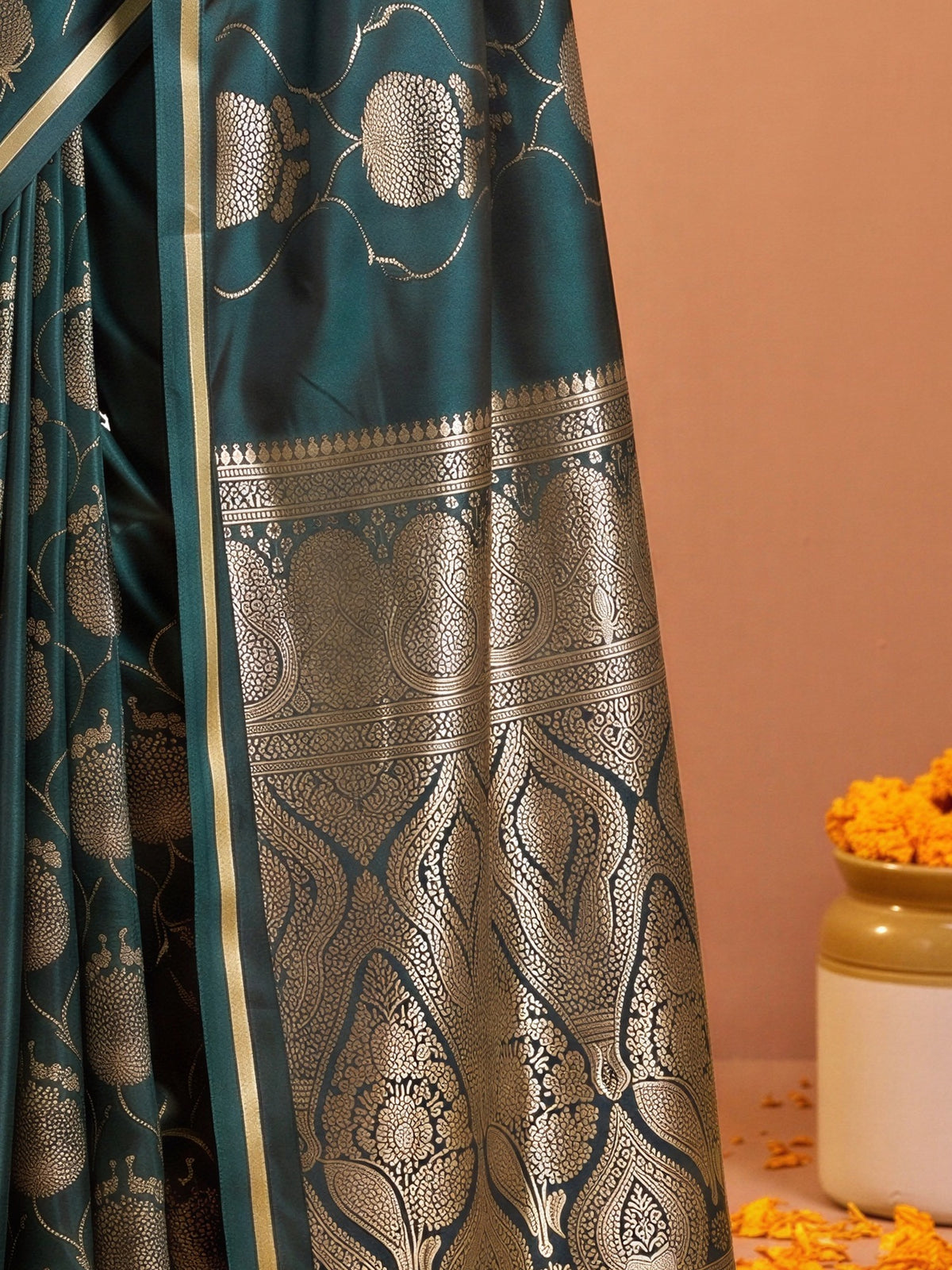 Pallu detail of green satin saree showing zari butta (metallic motif) work and zari border