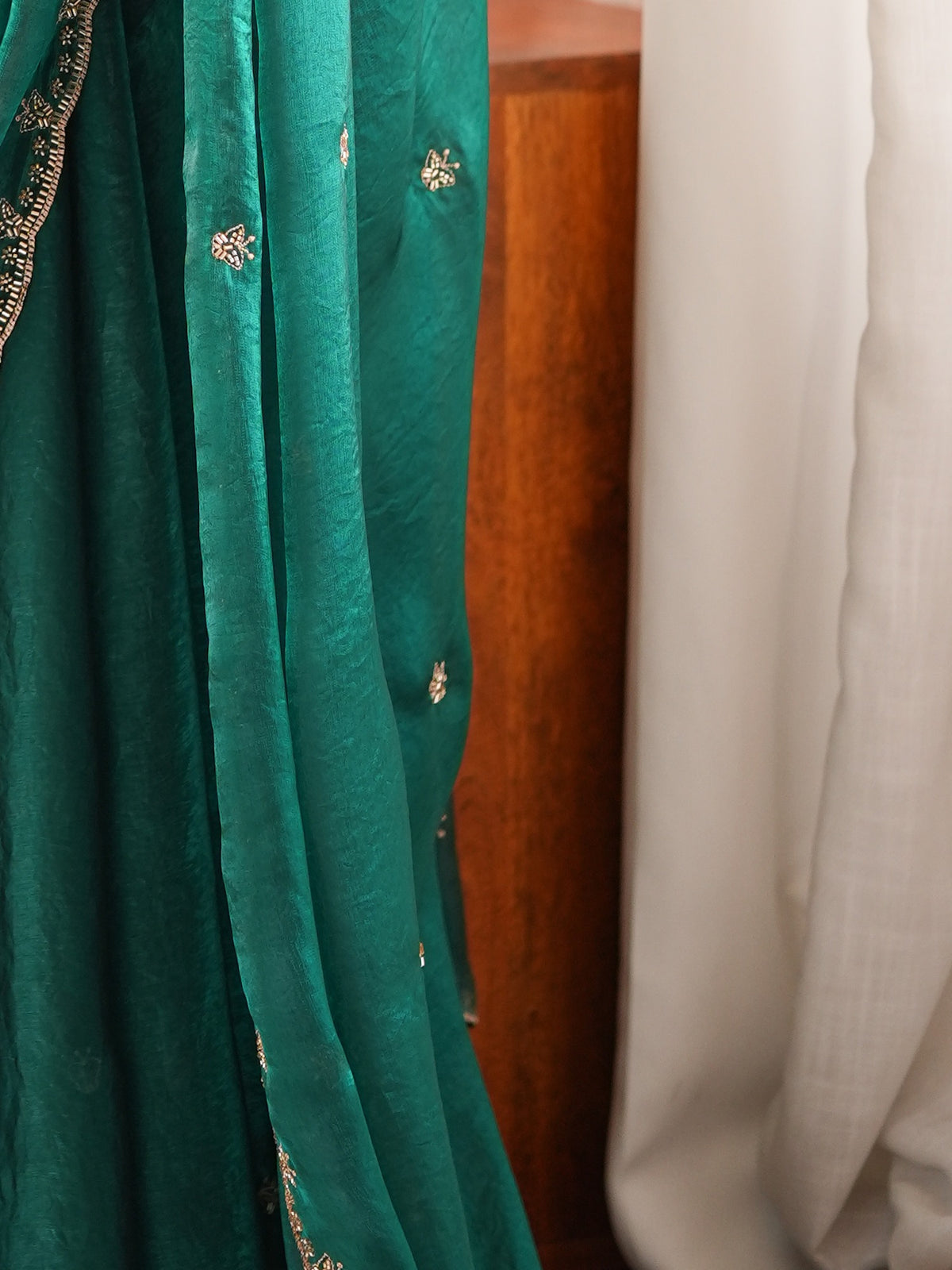 Pallu detail of teal green satin saree showing ornamented surface design and embellished border
