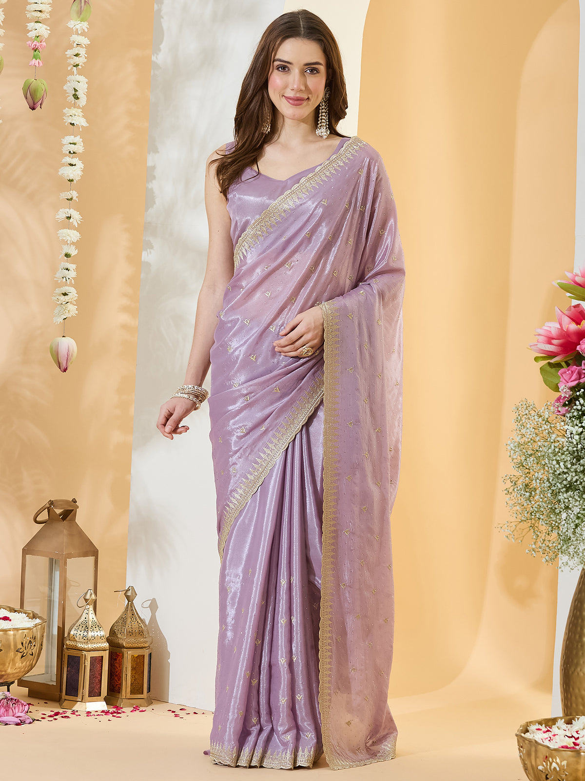 Woman wearing lavender satin saree with ornamented surface design and lavender blouse