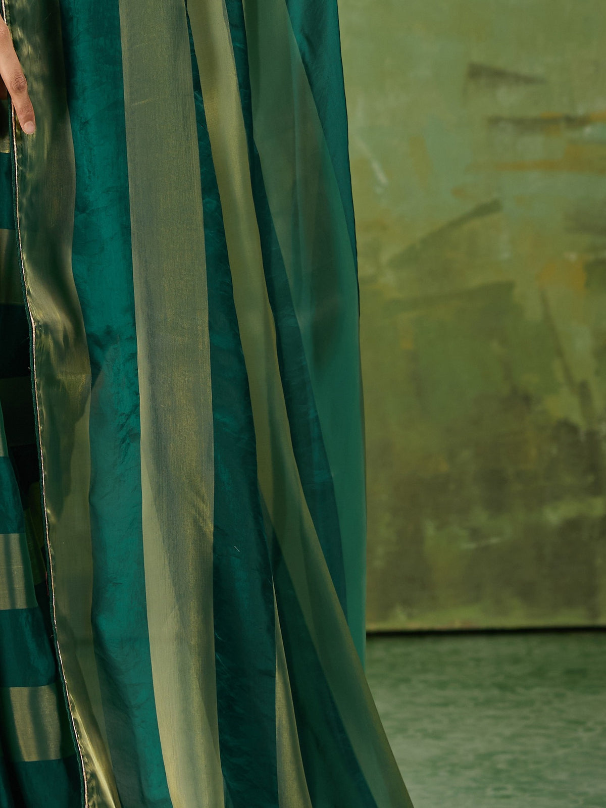 Pallu detail of teal green satin silk saree showing colour-blocked design and zari border