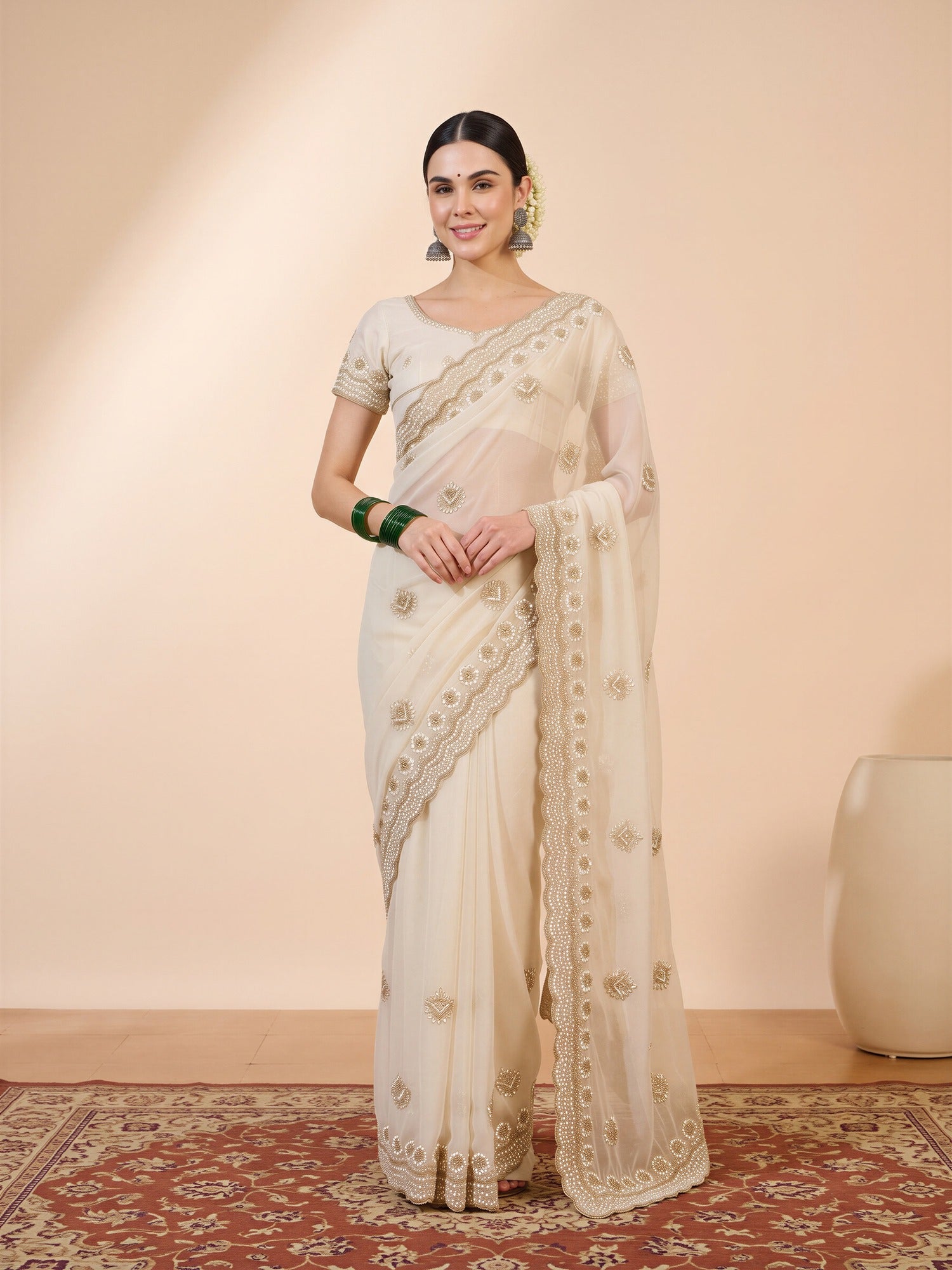 Woman wearing off white georgette saree with embroidered motif work and off white blouse