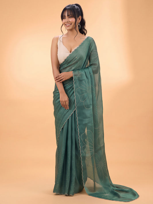 Woman wearing teal green satin silk saree with ornamented surface design and white blouse