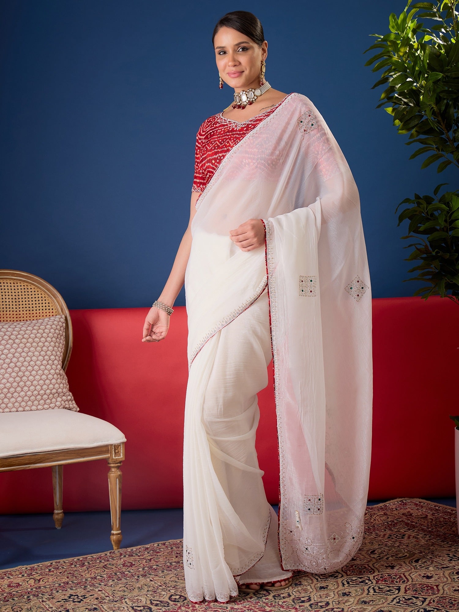 Woman wearing white chiffon saree with ornamented surface design and red blouse